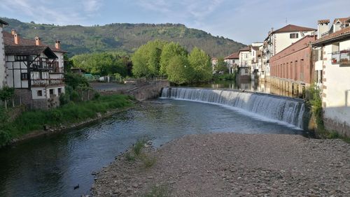 Scenic view of river by buildings against sky