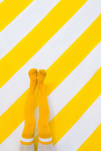 Unrecognizable woman in retro leggins on trend striped yellow background. positive sunny 