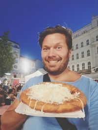 Portrait of smiling man holding ice cream against built structure