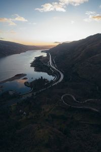 Scenic view of road by mountains against sky during sunset