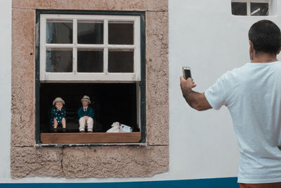 Man photographing through smart phone on window