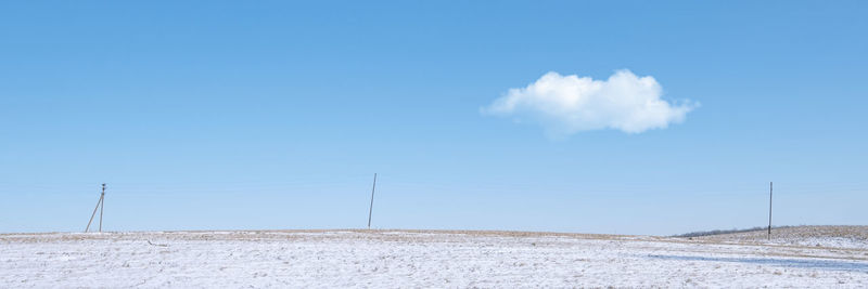 Nature background with copyspace.  winter park snow field, power poles blue sky white cloud.  