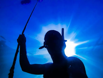 Silhouette man swimming undersea during sunny day