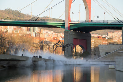 Bridge over river in city against sky