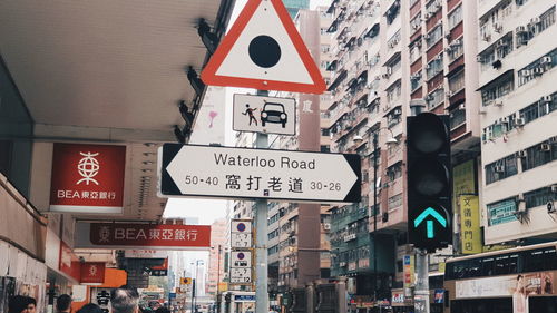 Low angle view of road signs against buildings in city
