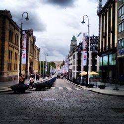 View of city street against cloudy sky