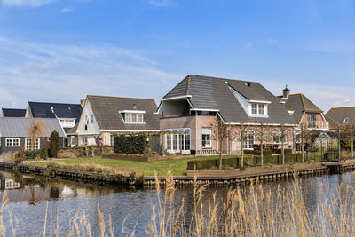 Buildings by lake against sky