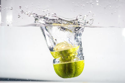 Close-up of fruit on glass over water against white background