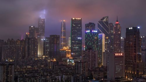 Illuminated buildings in city against sky at night