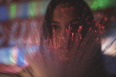 Close-up portrait of young woman with illuminated fiber optics in darkroom