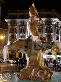 Close-up of statue against illuminated city at night