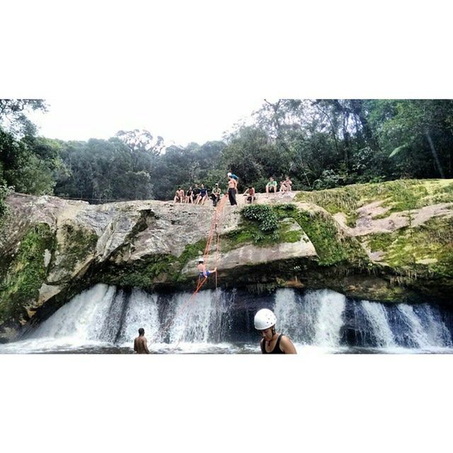 water, leisure activity, men, lifestyles, animal themes, tree, clear sky, domestic animals, nature, rock - object, beauty in nature, pets, person, mammal, waterfall, scenics, river, mountain, rear view