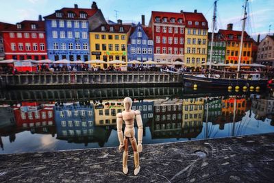 Rear view of shirtless man in canal against buildings in city