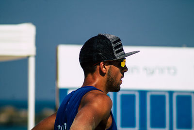 Side view of young man looking away against sky