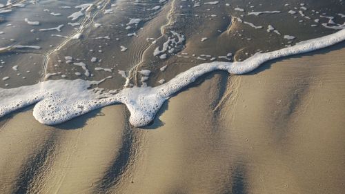 High angle view of surf reaching on shore at beach