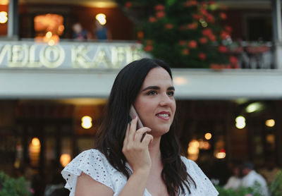 Candid portrait of happy young woman talking on the phone in city