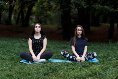 The relaxed girls is doing yoga in the park on carpet