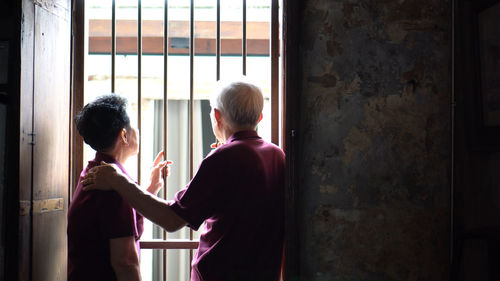 Rear view of man and woman standing on window