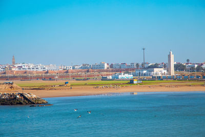 View of city by sea against blue sky