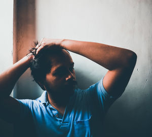 Close-up portrait of young man standing against wall at home