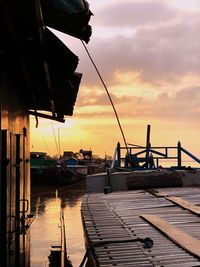 Sailboats moored on pier by sea against sky during sunset