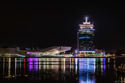 Illuminated city by water at night