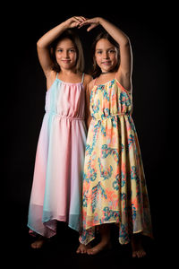 Portrait of girl standing with sister on black background