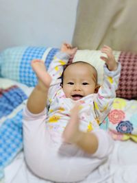 Portrait of cute baby girl on bed at home