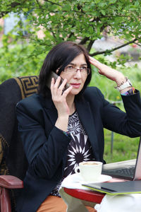 Young woman using mobile phone while sitting on table