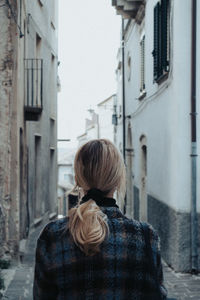 Rear view of woman standing on street against buildings