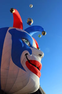 Low angle view of inflatable clown head against clear sky