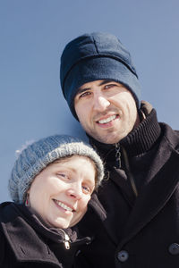 Portrait of couple smiling while standing against clear blue sky