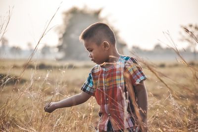 Boy standing on field against sky