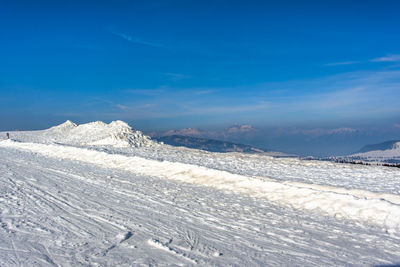 Glimpses of snow on monte grappa with blue sky and green trees, vicenza