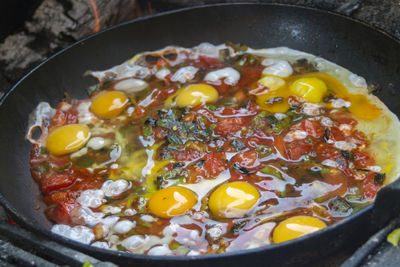 A dish of peppers, onions and eggs, and green spices on a pan prepared in a mobile oven.