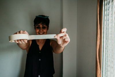 Portrait of senior woman standing against wall at home