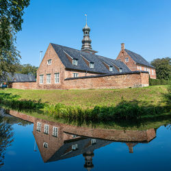 Reflection of building on lake against clear blue sky