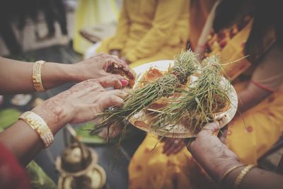Midsection of woman holding religious equipment in plate during wedding ceremony