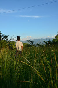 Rear view of man on field against sky