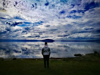 Rear view of man standing on lakeshore