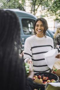 Smiling female customer buying fresh apples at farmer's market