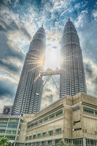 Low angle view of skyscrapers against cloudy sky