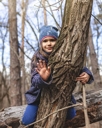 Portrait of girl holding tree trunk