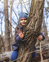 Portrait of boy holding tree trunk