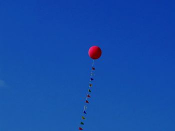 Low angle view of balloon with buntings against blue sky