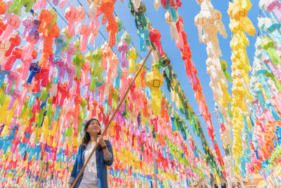 Smiling woman standing against multi colored paper lanterns