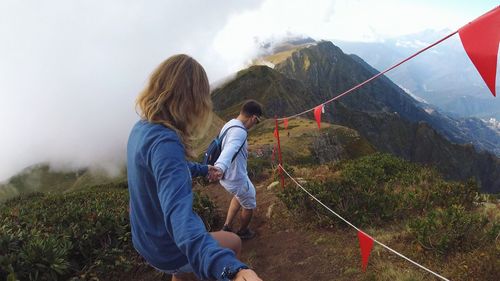 Friends climbing on mountain against sky