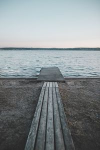 Wooden pier over sea against clear sky