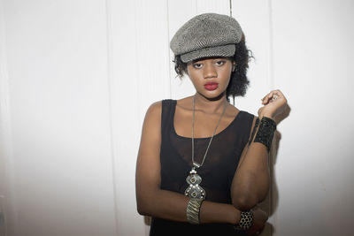 Portrait of beautiful young woman standing against wall