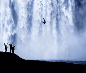 Silhouette people overlooking waterfall